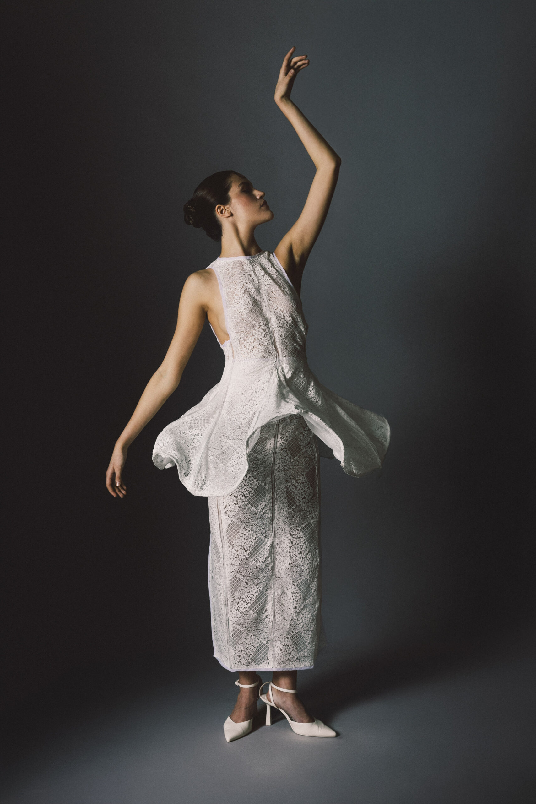 Fotografia de Raquerl Norte, que muestra una modelo con un vestido blanco y una mano levantada.
